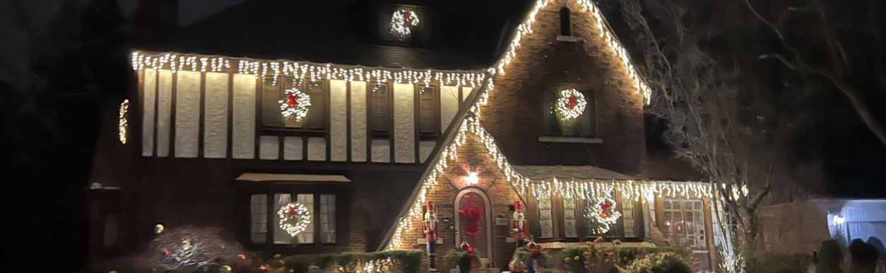 Tudor home with icicle lights along the roofline and lit wreaths in the windows